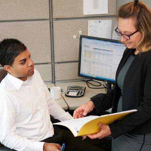 two employee talking at a desk