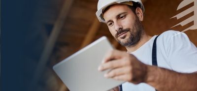 man wearing a hard hat and holding a tablet